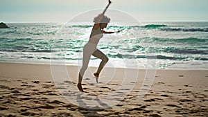 Active girl making gymnastics elements in front beautiful ocean waves sunny day.