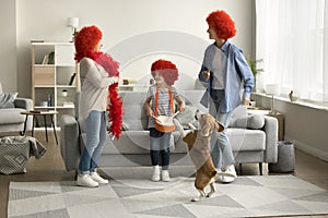 Active girl, mom, grandma in red wigs dancing with dog