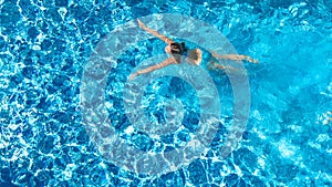 Active girl in swimming pool aerial drone view from above, young woman swims in blue water, tropical vacation