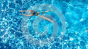 Active girl in swimming pool aerial drone view from above, young woman swims in blue water, tropical vacation