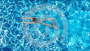 Active girl in swimming pool aerial drone view from above, young woman swims in blue water, tropical vacation