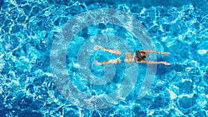 Active girl in swimming pool aerial drone view from above, young woman swims in blue water, tropical vacation, holiday on resort