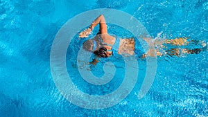 Active girl in swimming pool aerial drone view from above, young woman swims in blue water, tropical vacation, holiday on resort