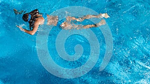 Active girl in swimming pool aerial drone view from above, young woman swims in blue water, tropical vacation, holiday on resort