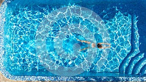 Active girl in swimming pool aerial drone view from above, young woman swims in blue water, tropical vacation, holiday on resort