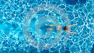 Active girl in swimming pool aerial drone view from above, young woman swims in blue water, tropical vacation, holiday on resort