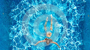 Active girl in swimming pool aerial drone view from above, young woman swims in blue water, tropical vacation, holiday on resort