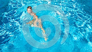 Active girl in swimming pool aerial drone view from above, young woman swims in blue water, tropical vacation, holiday on resort