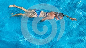 Active girl in swimming pool aerial drone view from above, young woman swims in blue water, tropical vacation, holiday on resort