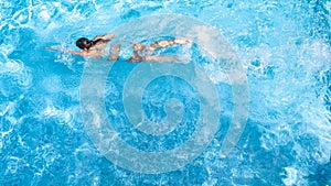 Active girl in swimming pool aerial drone view from above, young woman swims in blue water, tropical vacation, holiday on resort