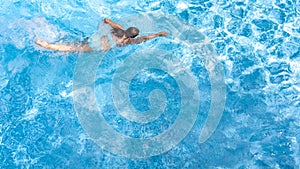 Active girl in swimming pool aerial drone view from above, young woman swims in blue water, tropical vacation, holiday on resort