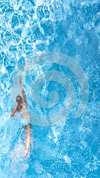 Active girl in swimming pool aerial drone view from above, young woman swims in blue water, tropical vacation, holiday on resort