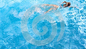 Active girl in swimming pool aerial drone view from above, young woman swims in blue water, tropical vacation, holiday on resort