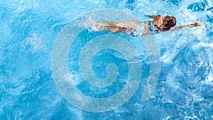 Active girl in swimming pool aerial drone view from above, young woman swims in blue water, tropical vacation, holiday on resort