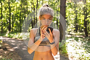 Active girl using fitness tracker smart watch jogging on summer nature outdoors looking at health data during sports