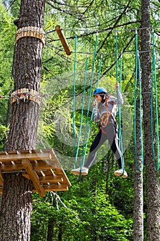 Active girl walking on suspended ropes in forest