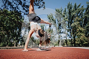 Two athletic women do cartwheels in a sunny park, showcasing their active lifestyle and love for fitness.