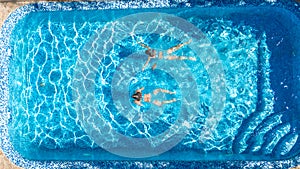 Active girls in swimming pool water aerial drone view from above, children swim, kids have fun on tropical family vacation