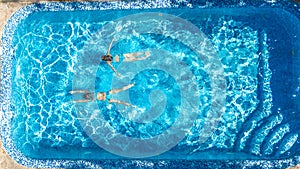 Active girls in swimming pool water aerial drone view from above, children swim, kids have fun on tropical family vacation