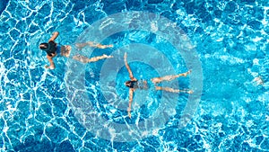 Active girls in swimming pool water aerial drone view from above, children swim, kids have fun on tropical family vacation