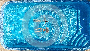 Active girls in swimming pool water aerial drone view from above, children swim, kids have fun on tropical family vacation