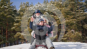 active grandma with grandson slides down the hill on a sled, child boy with a mobile phone shoots a video in a snowy
