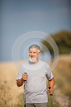 Active handsome senior man nordic walking outdoors