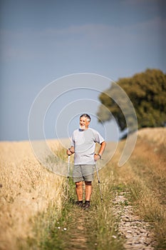 Active handsome senior man nordic walking outdoors