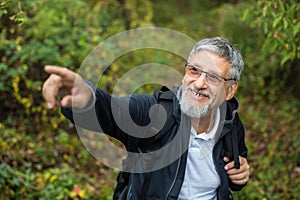 Active handsome senior man stoping for a moment while nordic walking