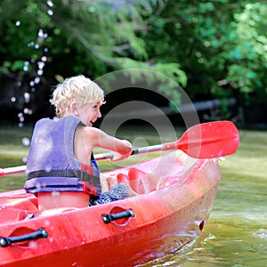 Active happy boy kayaking on the river