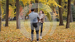 Active happy caucasian married couple lovers two positive teenagers spinning in autumn park hold hands jumping on leaves