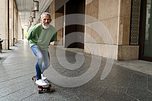 Active happy cool older man skater riding skateboard in the city street.