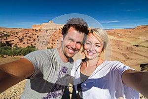 Active happy couple taking selfie on travel at Ait Benhaddou kasbah, Ouarzazate, Morocco.