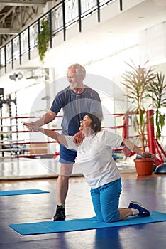 Active happy elderly couple exercising in gym.