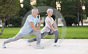 Active happy elderly family couple in sportswear working out together in city park on sunny morning photo