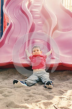 Active happy funny smiling Caucasian boy child sliding on playground schoolyard outdoor on summer sunny day