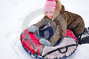 Active happy girl sliding down a snowy hill on a snow tubing, sledding in the park in the snowy air. The concept of a