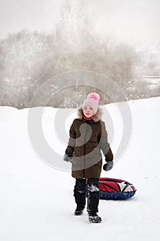 Active happy girl sliding down a snowy hill on a snow tubing, sledding in the park in the snowy air. The concept of a