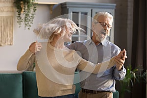 Active happy mature couple have fun dancing at home