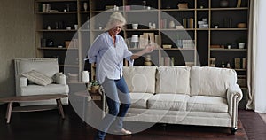 Active happy mature woman dancing in living room