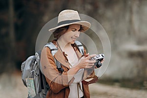 Active healthy Caucasian woman taking pictures with an vintage film camera on a forest rocks