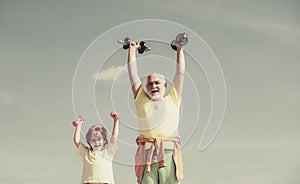 Active healthy life for family. Senior man and child exercising on blue sky. Grandfather and child in gym working out