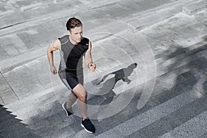 Active and healthy lifestyle. Guy in sportswear runs up the city stairs