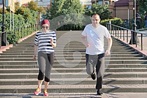 Active healthy lifestyle of mature couple. Middle-aged man and woman running upstairs