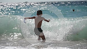 active healthy little boy with diving mask playing with stom sea ocean waves during summer vacation leisure activity in