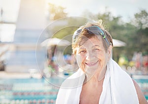 Active healthy senior woman (over the age of 50) in sport goggles and with towel smiling after swimming.