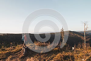 Active hiker enjoys the feeling of reaching the top of the mountain at sunrise. A hiker is enlightened by the morning sun and