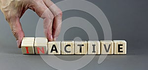Active or inactive symbol. Businessman turns wooden cubes and changes the word Inactive to Active. Beautiful grey table grey