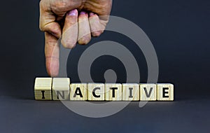 Active or inactive symbol. Businessman turns wooden cubes and changes the word Inactive to Active. Beautiful grey table grey