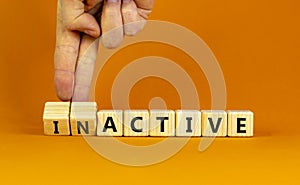 Active or inactive symbol. Businessman turns wooden cubes and changes the word Inactive to Active. Beautiful orange table orange